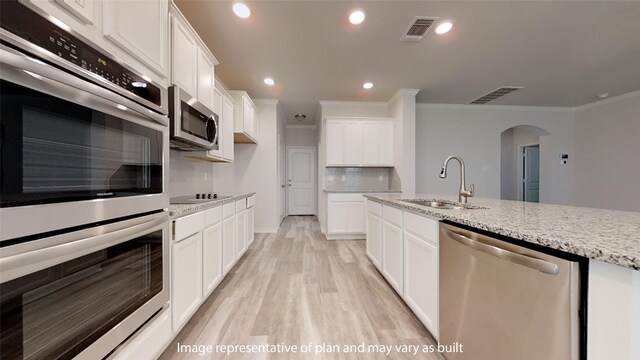 kitchen with white cabinetry, light stone countertops, sink, stainless steel appliances, and crown molding