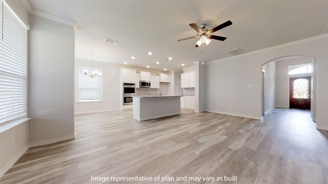 kitchen with white cabinetry, an island with sink, decorative light fixtures, appliances with stainless steel finishes, and light wood-type flooring