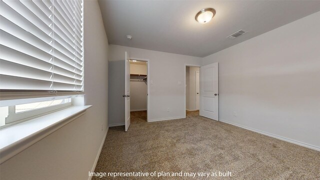 unfurnished bedroom with a spacious closet, a closet, and carpet floors