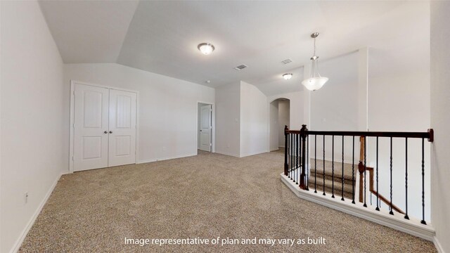 spare room featuring light colored carpet and lofted ceiling