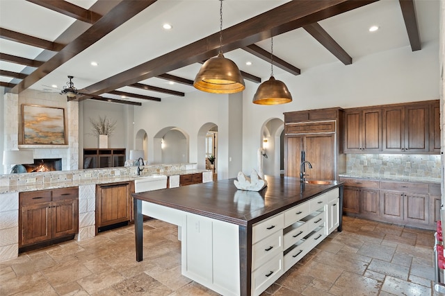 kitchen with pendant lighting, a spacious island, ceiling fan, beam ceiling, and white cabinetry