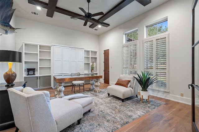 living room featuring ceiling fan, wood-type flooring, and a high ceiling