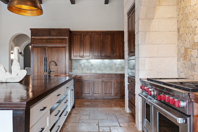 kitchen featuring decorative backsplash, appliances with stainless steel finishes, dark brown cabinetry, sink, and white cabinets