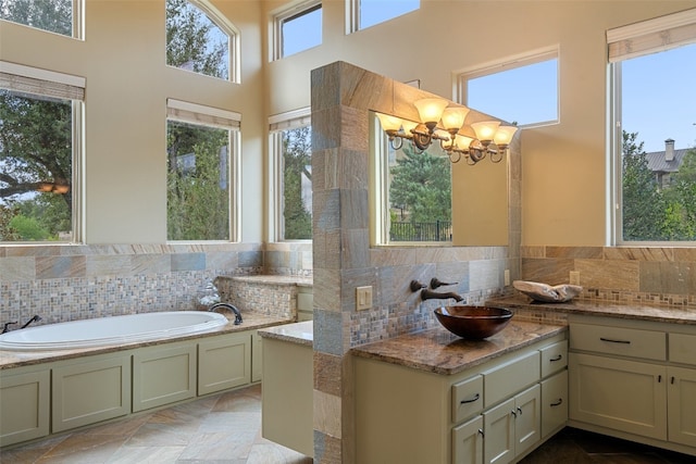 bathroom with a bathing tub, a wealth of natural light, vanity, and a chandelier