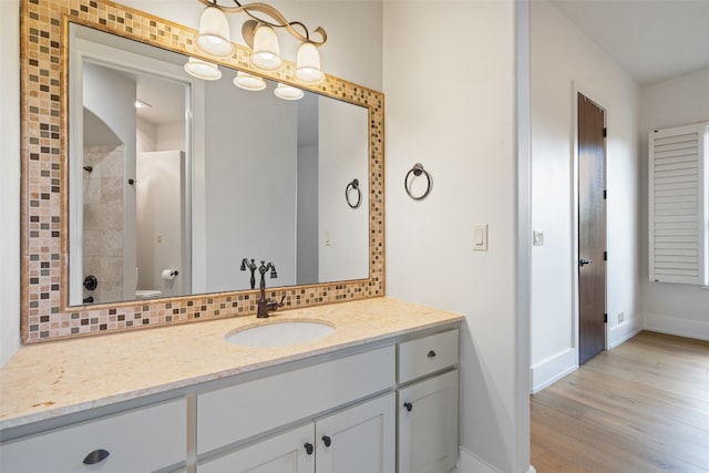 bathroom with walk in shower, backsplash, hardwood / wood-style floors, toilet, and vanity