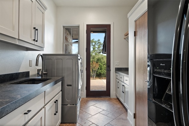 kitchen featuring white cabinets, stainless steel fridge, washer and clothes dryer, and sink