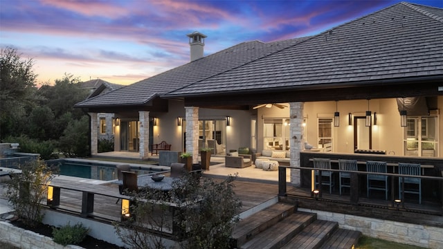 back house at dusk featuring a swimming pool side deck