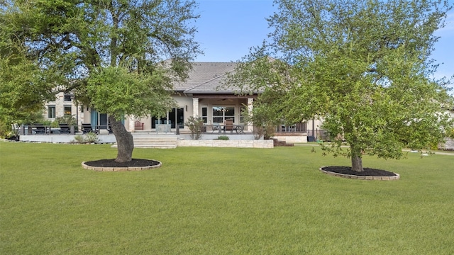 rear view of property with ceiling fan and a yard