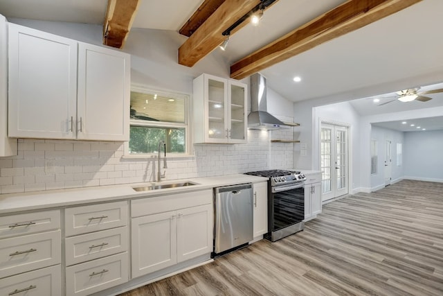 kitchen featuring tasteful backsplash, stainless steel appliances, sink, wall chimney range hood, and white cabinets