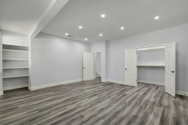 unfurnished bedroom featuring hardwood / wood-style floors and a walk in closet