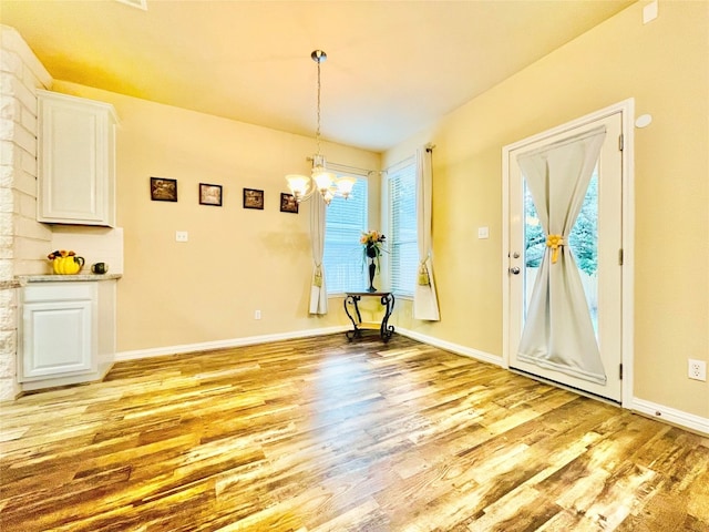 unfurnished dining area with light wood-type flooring and a chandelier