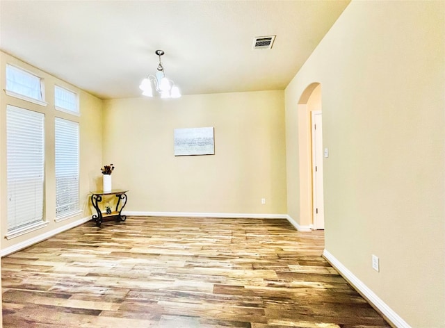 unfurnished room with light wood-type flooring and a chandelier