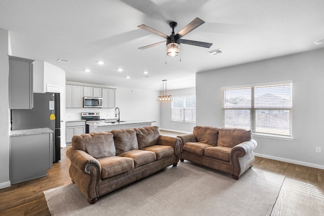 living room featuring ceiling fan, wood-type flooring, and sink