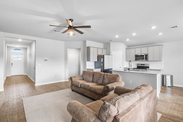 living room with ceiling fan, sink, and light wood-type flooring