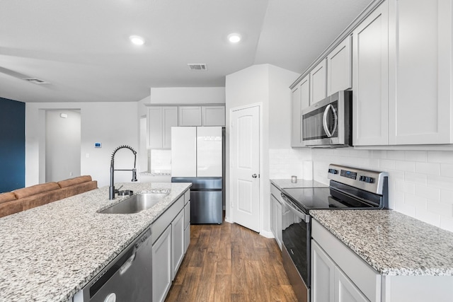 kitchen featuring decorative backsplash, appliances with stainless steel finishes, sink, dark hardwood / wood-style floors, and an island with sink