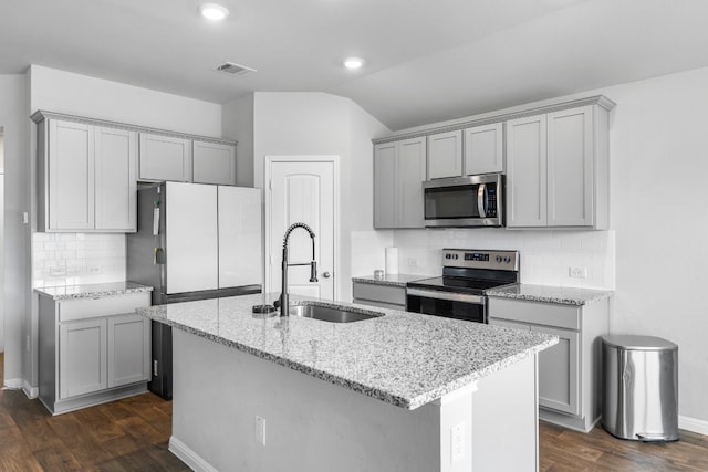 kitchen with dark hardwood / wood-style flooring, stainless steel appliances, a kitchen island with sink, and backsplash