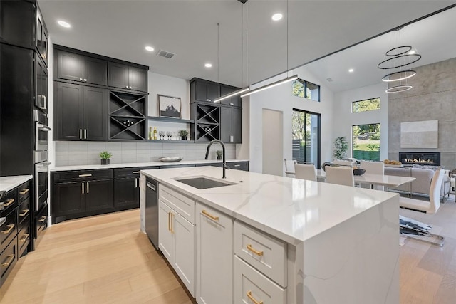 419 Hazeltine Dr, Lakeway, TX 78734 - kitchen with open shelves, light wood finished floors, stainless steel appliances, dark cabinets, and an island with sink