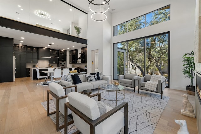 living room featuring light hardwood / wood-style floors, a high ceiling, and a chandelier