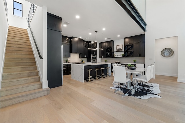 dining space with light hardwood / wood-style floors and a high ceiling