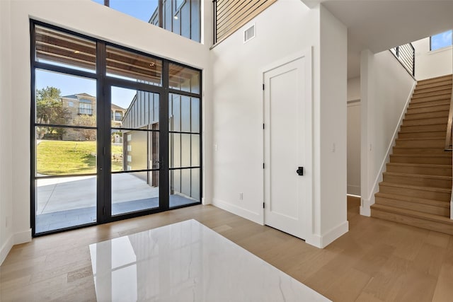 foyer entrance with light hardwood / wood-style floors and a high ceiling