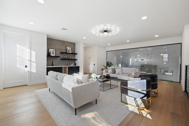 living room featuring bar, light hardwood / wood-style flooring, and a notable chandelier