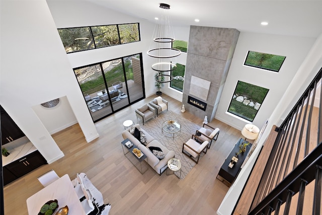 living room with a fireplace, light hardwood / wood-style flooring, and high vaulted ceiling