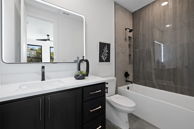 full bathroom featuring vanity, tile patterned floors, tiled shower / bath, ceiling fan, and toilet