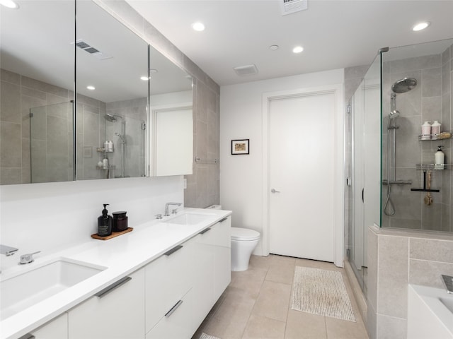 bathroom featuring tile patterned flooring, vanity, a shower with shower door, and toilet