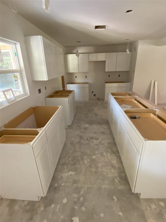 kitchen featuring washer and clothes dryer, a kitchen island, and white cabinetry