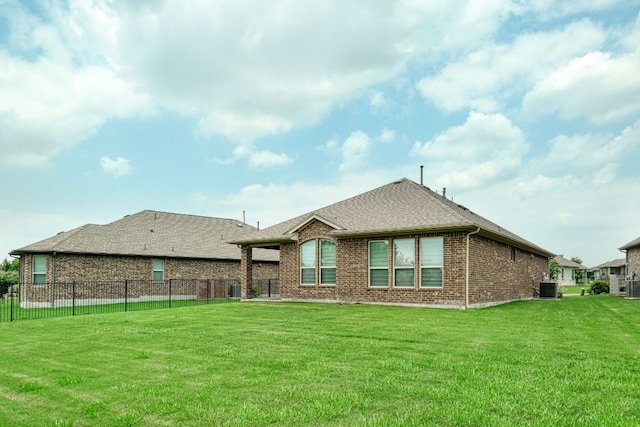 back of property with a yard and central AC