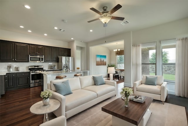 living room with ceiling fan with notable chandelier, dark hardwood / wood-style flooring, and a wealth of natural light