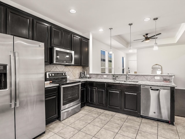 kitchen featuring ceiling fan, sink, light stone countertops, a raised ceiling, and appliances with stainless steel finishes