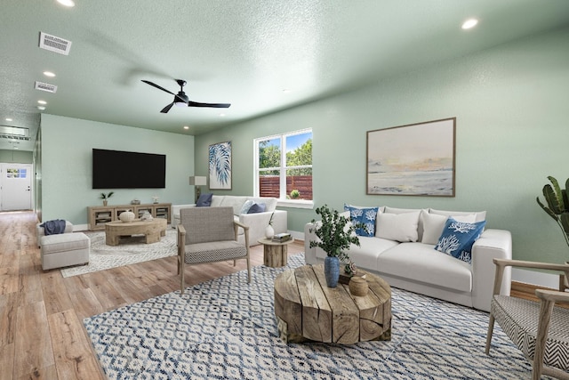 living room featuring hardwood / wood-style floors, ceiling fan, and a textured ceiling