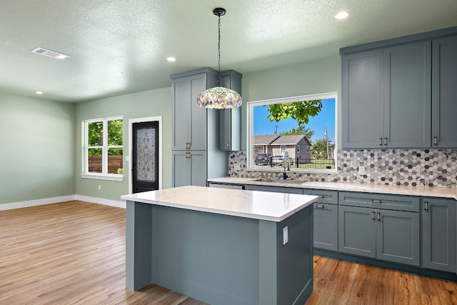 kitchen with gray cabinets, a center island, pendant lighting, and sink