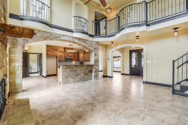 unfurnished living room featuring a high ceiling and ceiling fan