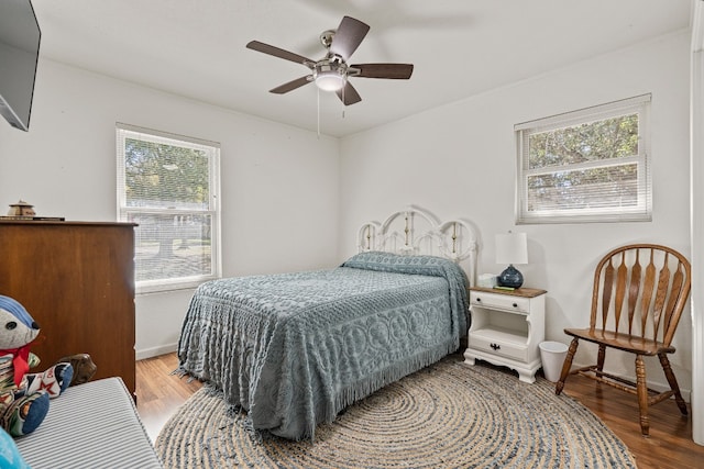 bedroom with wood-type flooring, multiple windows, and ceiling fan