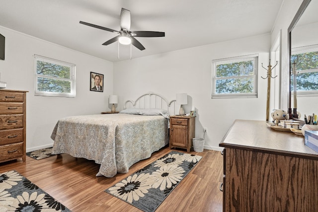 bedroom featuring multiple windows, light hardwood / wood-style floors, and ceiling fan