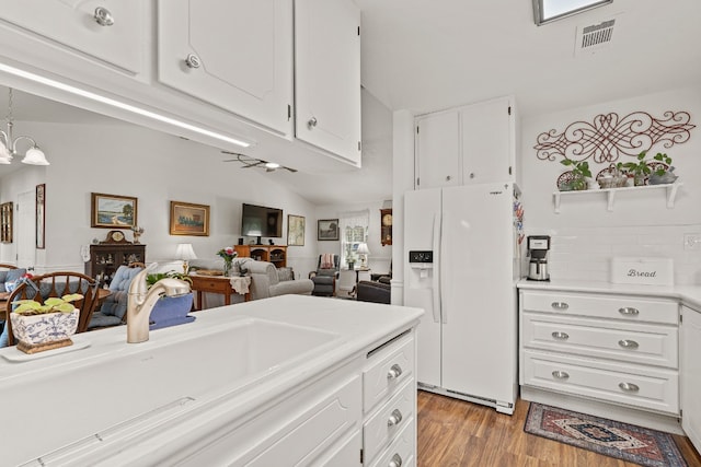 kitchen with white cabinetry, white fridge with ice dispenser, light hardwood / wood-style floors, and sink