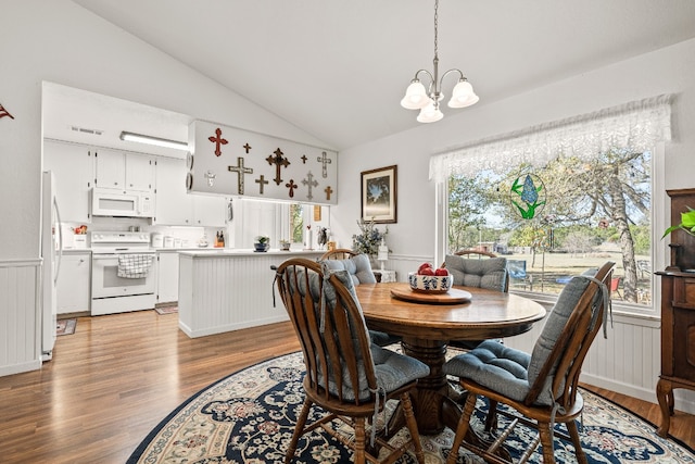 dining area with a notable chandelier, lofted ceiling, a wealth of natural light, and light hardwood / wood-style flooring