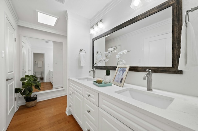 bathroom featuring toilet, vanity, wood-type flooring, and ornamental molding