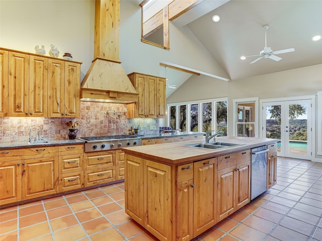 kitchen with high vaulted ceiling, french doors, a center island with sink, tasteful backsplash, and stainless steel appliances