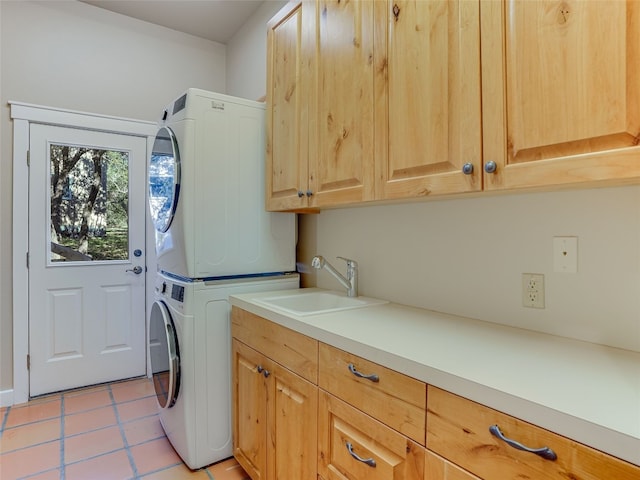 laundry area with stacked washer and dryer, light tile patterned floors, cabinets, and sink