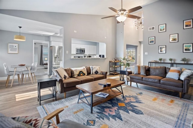 living room with ceiling fan, high vaulted ceiling, and light hardwood / wood-style floors