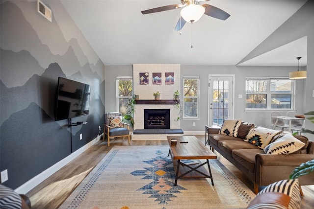 living room with ceiling fan, a fireplace, hardwood / wood-style floors, and vaulted ceiling