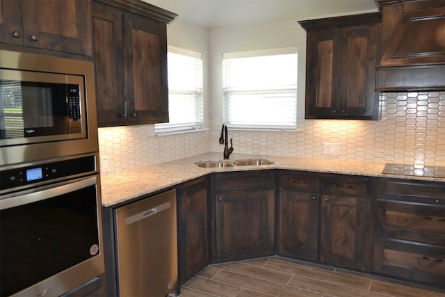 kitchen with sink, light hardwood / wood-style flooring, dark brown cabinets, light stone counters, and stainless steel appliances