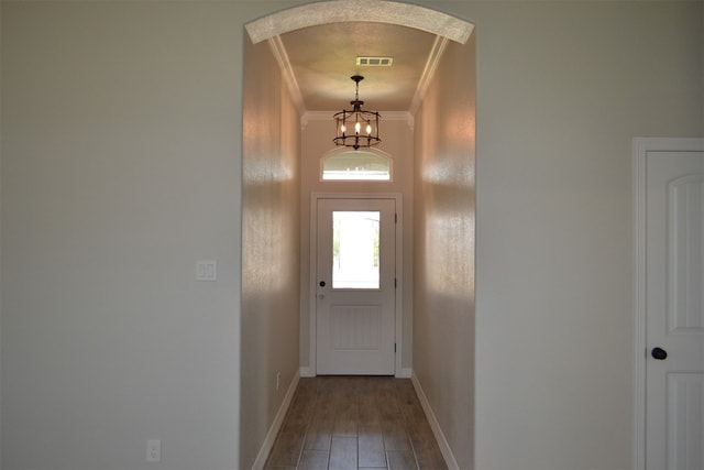 doorway with hardwood / wood-style flooring, an inviting chandelier, and ornamental molding