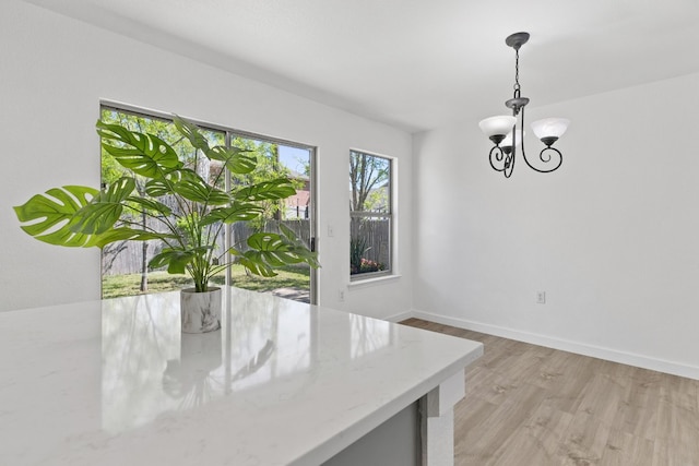 unfurnished dining area with light hardwood / wood-style floors and an inviting chandelier