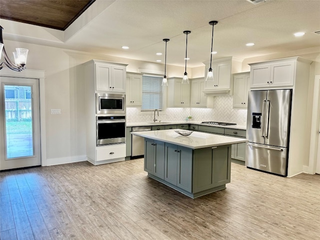 kitchen with a center island, light wood-type flooring, decorative light fixtures, and appliances with stainless steel finishes