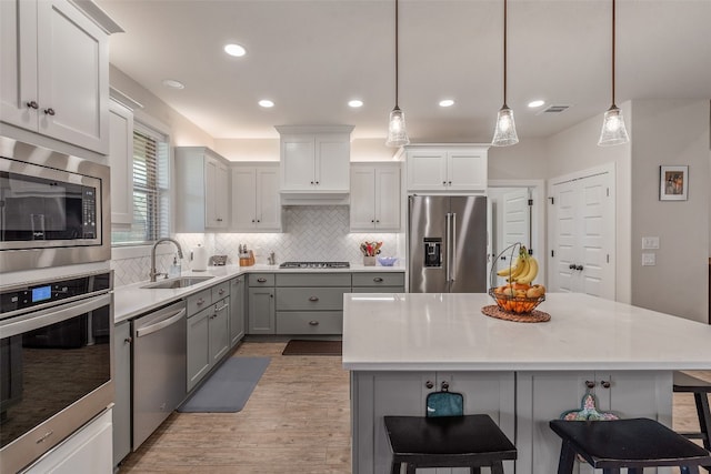 kitchen featuring pendant lighting, sink, stainless steel appliances, and a breakfast bar area