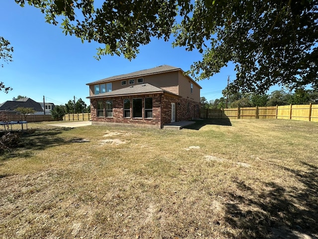 back of house featuring a lawn and a trampoline